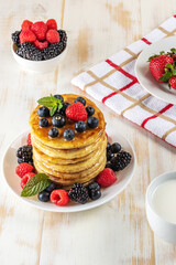 Delicious pancakes with fresh berries on white wooden table. Food concept.