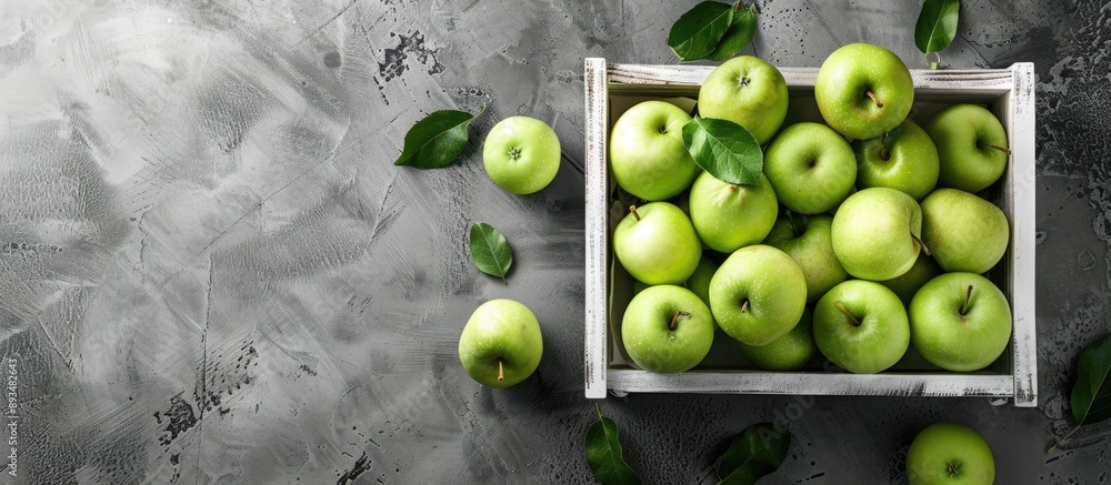 Poster Fresh green apples arranged in a white wooden box on a rustic gray table with copy space image available