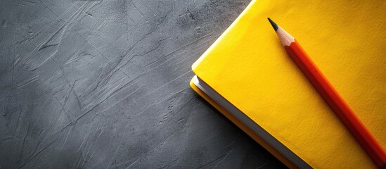 Gray background enhances the yellow notepad and pencil creating a visually appealing copy space image