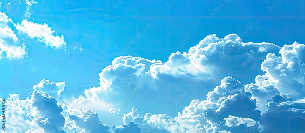 Fototapete A vivid blue sky with dense white clouds providing a perfect backdrop for text or images with enough room on the side for copy space image