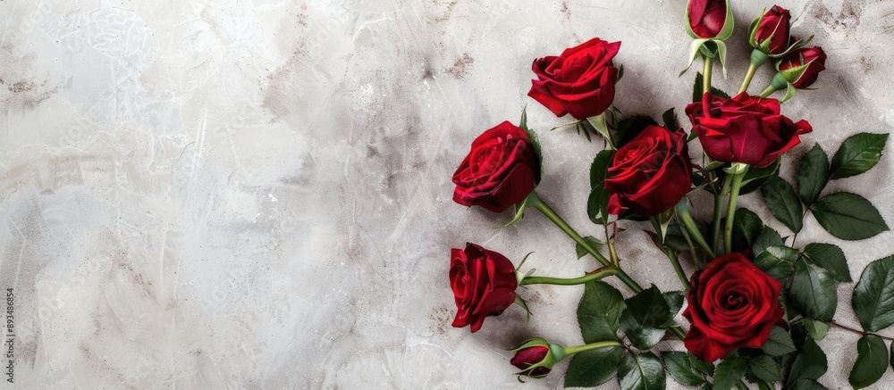 Poster flat lay scene captured from above featuring a rose bouquet with leaves on a light table providing a