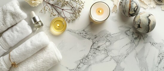 On a marble table there s a picture featuring spa essentials such as a white towel candle aroma oil and herbal compressing balls with copy space image