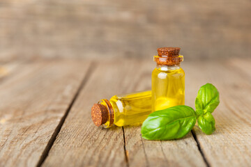 Basil essential oil on a textured wooden background. Basil essential oil and fresh leaves. Aromatherapy. Aroma oil. Medical herbs. Alternative medicine. Place for text. Copy space.