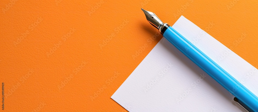 Poster a colorful blue ballpoint pen next to a blank white rectangle paper on an orange paper background wi