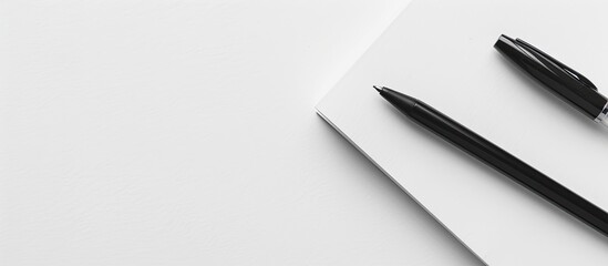 A classic pairing of a white notepad and a black pen perfect for taking notes or sketching creating a timeless look in a copy space image
