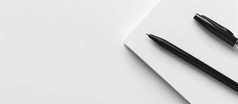 A classic pairing of a white notepad and a black pen perfect for taking notes or sketching creating a timeless look in a copy space image
