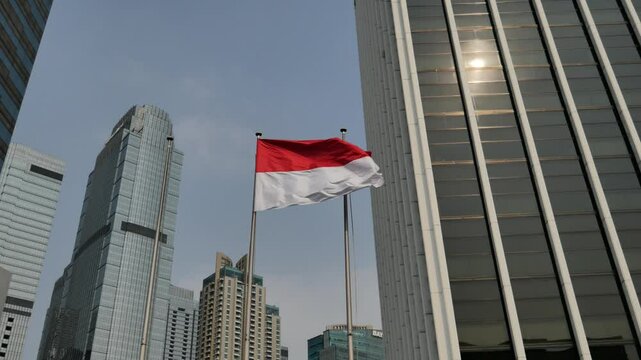 Indonesian flag flying outdoors against the backdrop of blue sky and tall buildings of the capital, BCA summitmas
