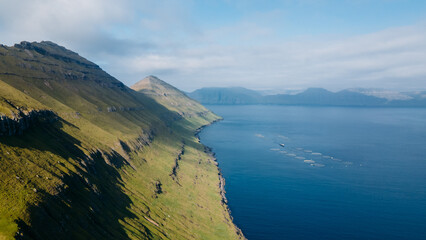 Funningur village, Faroe Islands. Sunny day in summer. Amazing nature in Faroe Islands. Eysturoy Island. Gonguturur or Hvithamar Trailhead. Faroese fjord and summits