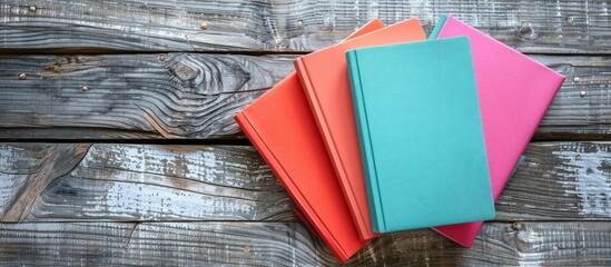 Flat lay of three vibrant planners displayed on a wooden surface with copy space image