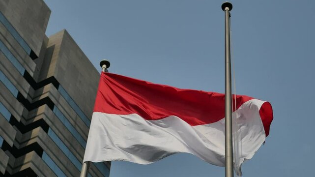Indonesian flag flying outdoors against the backdrop of blue sky and tall buildings of the capital, BCA summitmas