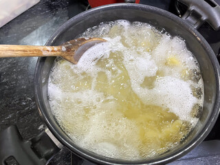 Pasta cooking in a pot with a wooden spoon.