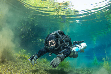 A diver using a rebreather diving in a crystal clear water of a river spring