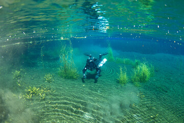 A diver using a rebreather diving in a crystal clear water of a river spring