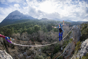 A tightrope walker walks along a rope stretched over a canyon.