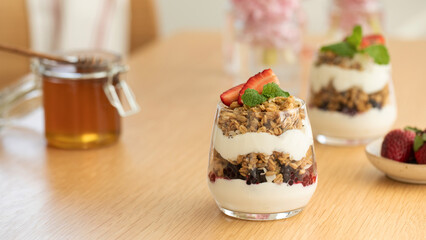 Yogurt with crispy granola, berries and honey for a delicious breakfast. Healthy eating.