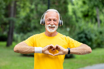 Active senior man showing heart shape and supporting healthy lifestyle. Retired man running...