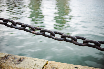 old rusty metall bollard with chains at seaside