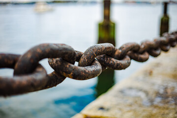 old rusty metall bollard with chains at seaside