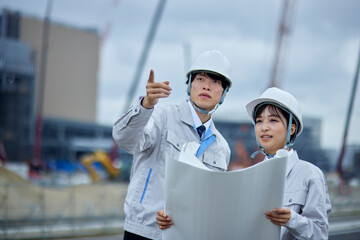 建設現場を視察するヘルメットを被り作業服を着たビジネスマンとビジネスウーマン