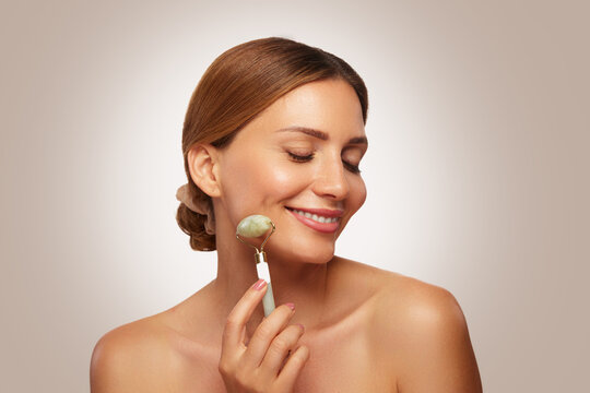 Woman uses jade roller on her face during skin care routine