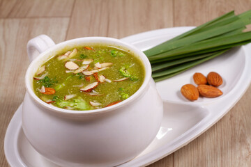 A bowl of broccoli soup with sliced almond and fresh vegetable
