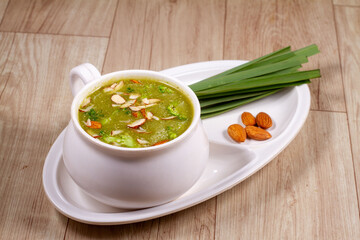 A bowl of broccoli soup with sliced almond and fresh vegetable