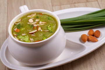 A bowl of broccoli soup with sliced almond and fresh vegetable