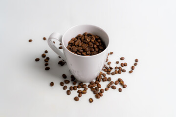arabica roasted coffee bean's spill from a white mug, isolated on white background