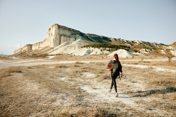 female hiker trekking through arid desert landscape with backpack and distant mountain scenery