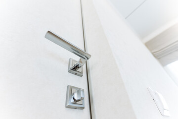 The stylish rectangular metal door handle, featured on a white door, combines automotive and...