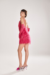 Fototapeta premium Elegant woman in pink dress faces away from the camera.