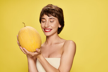 A captivating young woman in a white dress gracefully holds a ripe melon against a vibrant backdrop.