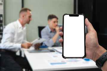 Business - technology and office concept - Hand holding mobile phone with blank screen in office.