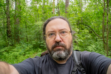 A serious middle-aged man takes a selfie in the forest. Scientist during wildlife research.