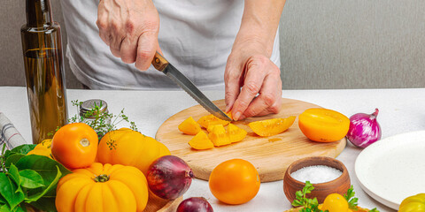 A woman is preparing a tomato salad. Ripe vegetables, herbs, aromatic spices, olive oil