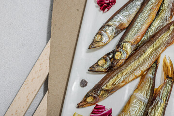 Smoked smelt with fresh lemon and herbs. Salted fish with marine decor. Trendy dish, sea rope