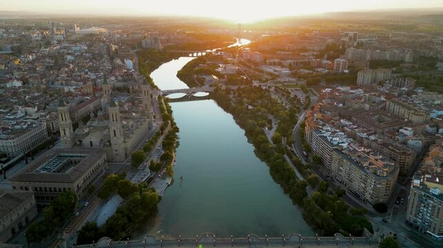 ZARAGOZA - Spain. Spectacular aerial view of historic and medieval city center of Zaragoza. Drone backwards above Ebro River. Spectacular orange sunset reflecting on buildings and landscape. Travel 