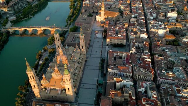 Rooftops of Zaragoza. Aerial drone point of view of historic city center of Zaragoza. View from above of Cathedral of Zaragoza, Plazza of Pillar, Ebro River. Camera tilt down. Drone circling. Sunset