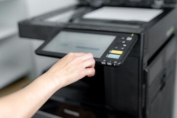 A girl sets up a photocopier to print and copy a document.