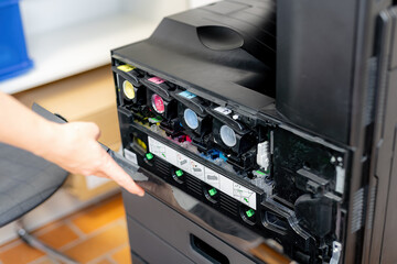 A girl checks the paint in a color laser printer.