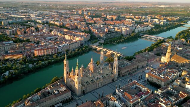 Spectacular 4K aerial view of city center of ZARAGOZA, Spain. View of Zaragoza Cathedral, River Ebro and Stone Bridge in background. Beautiful warm colours at sunset. Drone circling above old town.