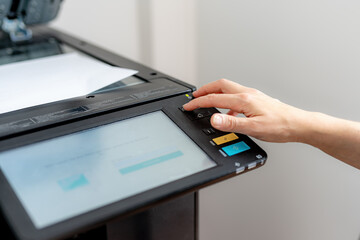 A girl sets up a photocopier to print and copy a document.