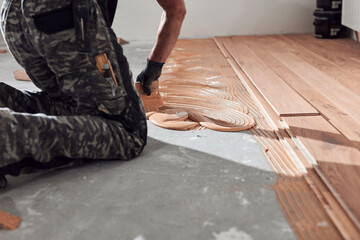 Professional handyman installing laminate flooring in a new apartment.