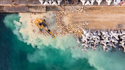 Waterfront construction site with excavator. Excavator working on a breakwater construction