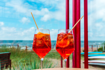 Couple Aperol Spritz Cocktail. Alcoholic beverage based on outdoor cafe table with ice cubes and oranges. Beach summer blue sky.