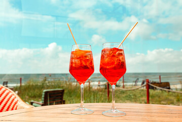 Aperol Spritz Cocktail. Alcoholic beverage based on outdoor cafe table with ice cubes and oranges. Beach summer blue sky.