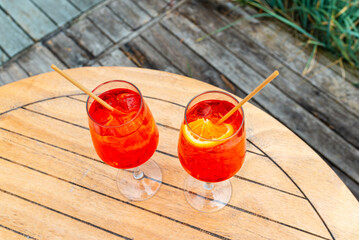 Orange slice and two glasses of aperol spritz cocktails on a table, summer vacation, holiday.