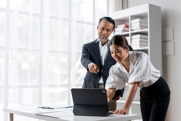 A man and a woman are looking at a laptop together