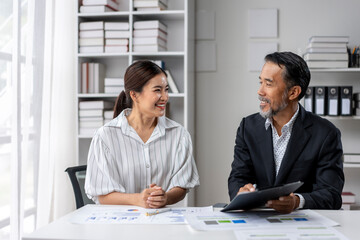 Fototapeta premium Two people are sitting at a desk, one of them holding a clipboard