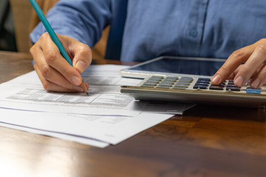 Close up of muslim woman using calculator and tablet doing math finance on an wooden desk, tax, report, accounting, statistics, and analytical research concept